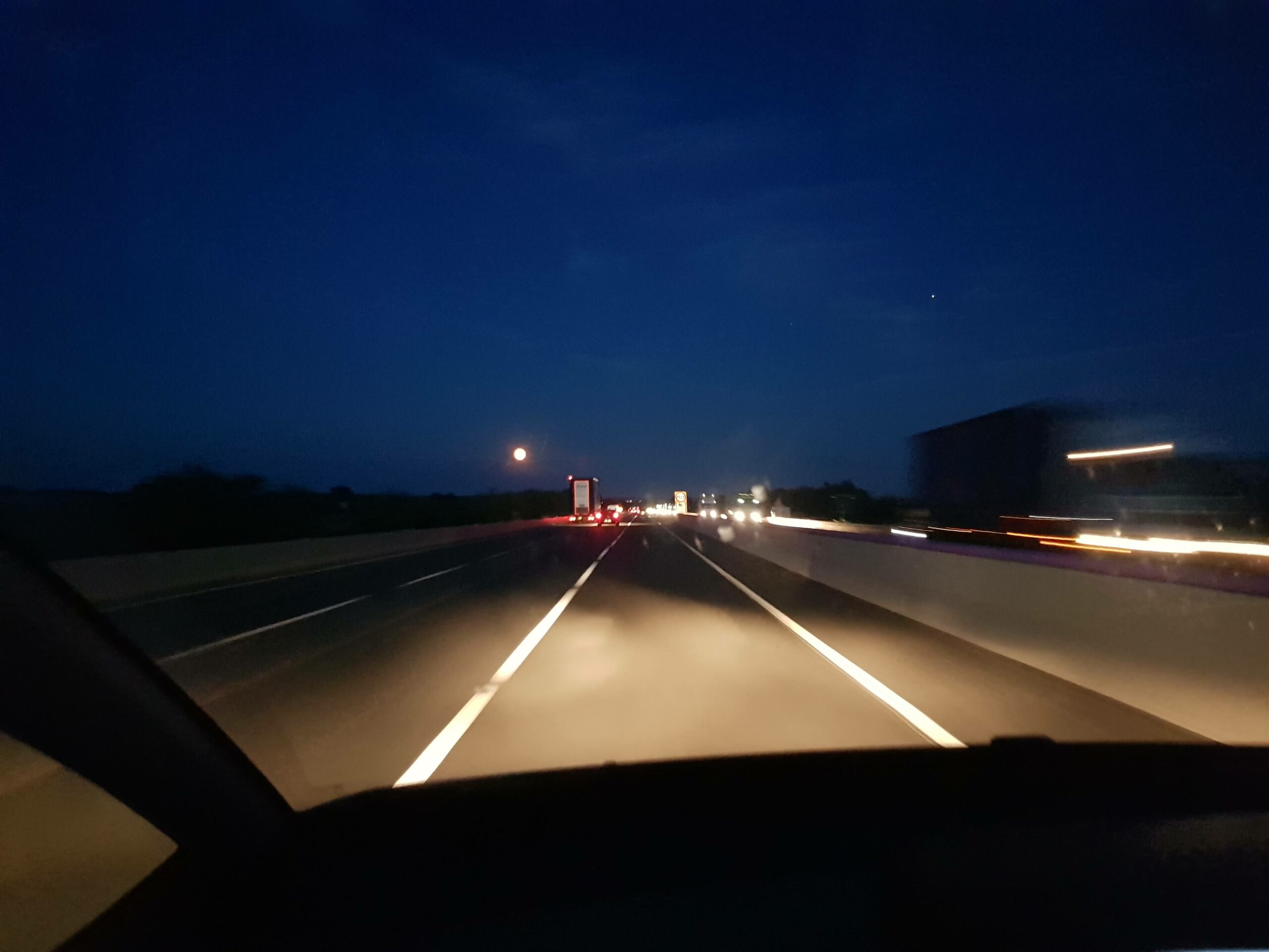 View from the passenger seat of a car along a moonlit motorway