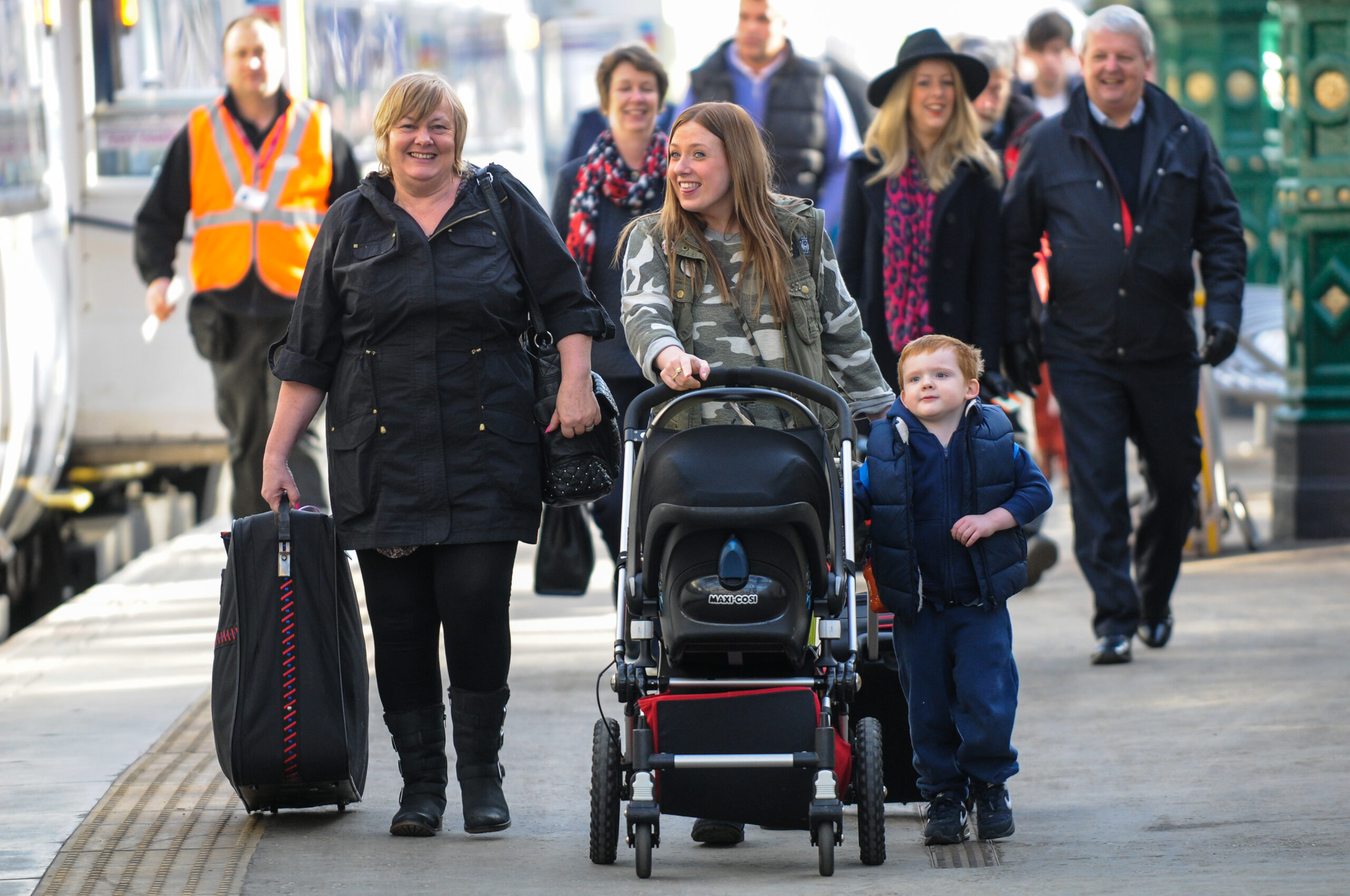 Smiling passengers at a train station platform.