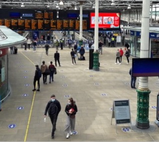 Webpage banner picture: Passengers walking through a train station.